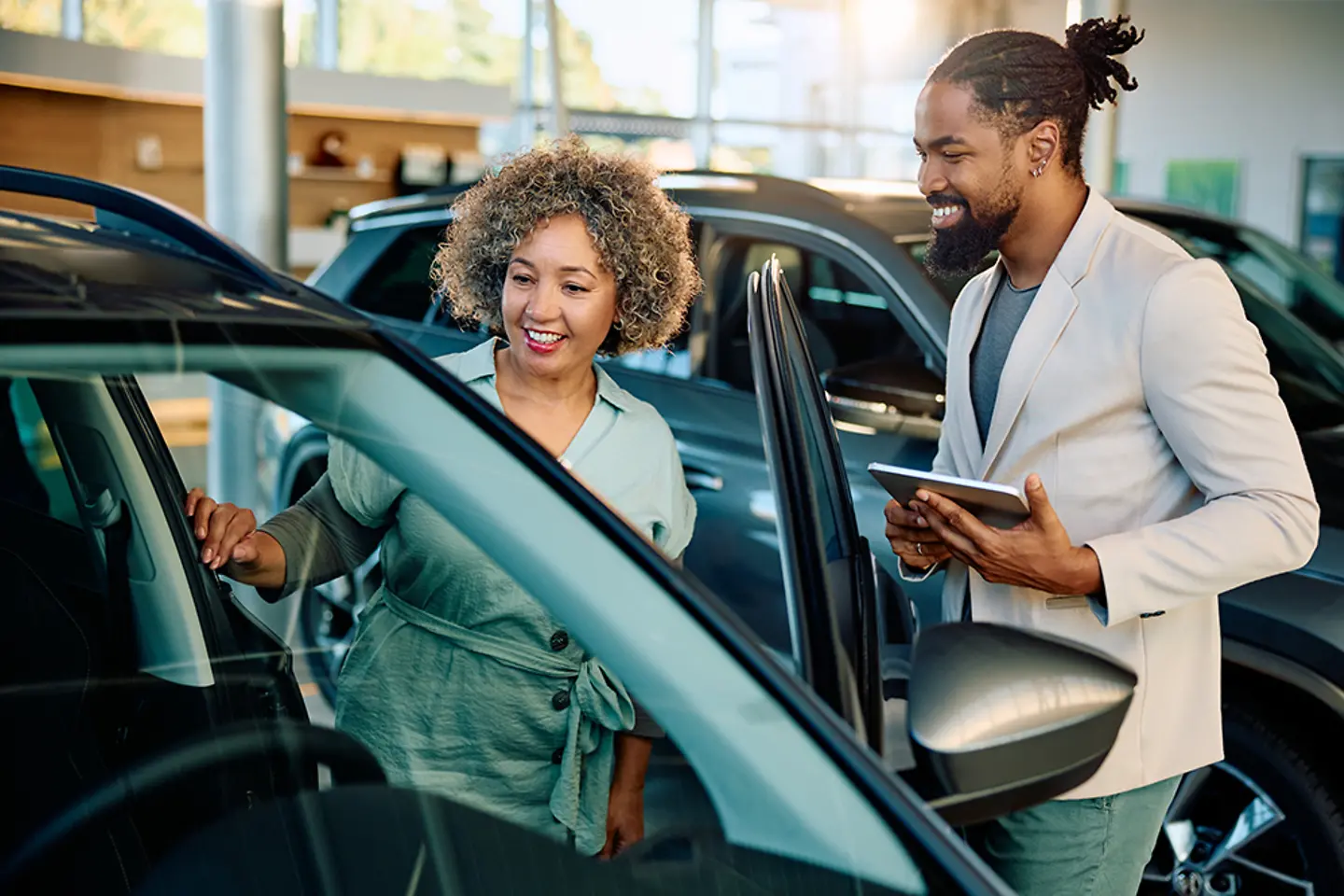 Happy customer buying new car with salesman in showroom