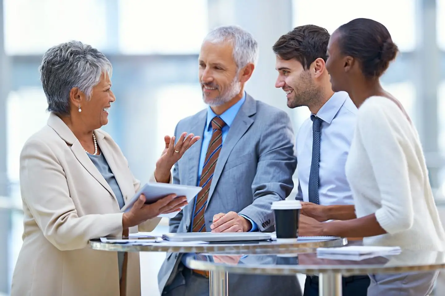 Business partners from different nations in discussion with each other around a bar table
