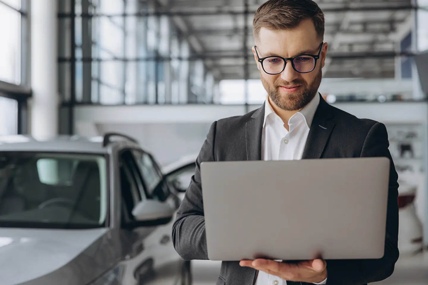 Ein Autoverkäufer mit Laptop im Autohaus