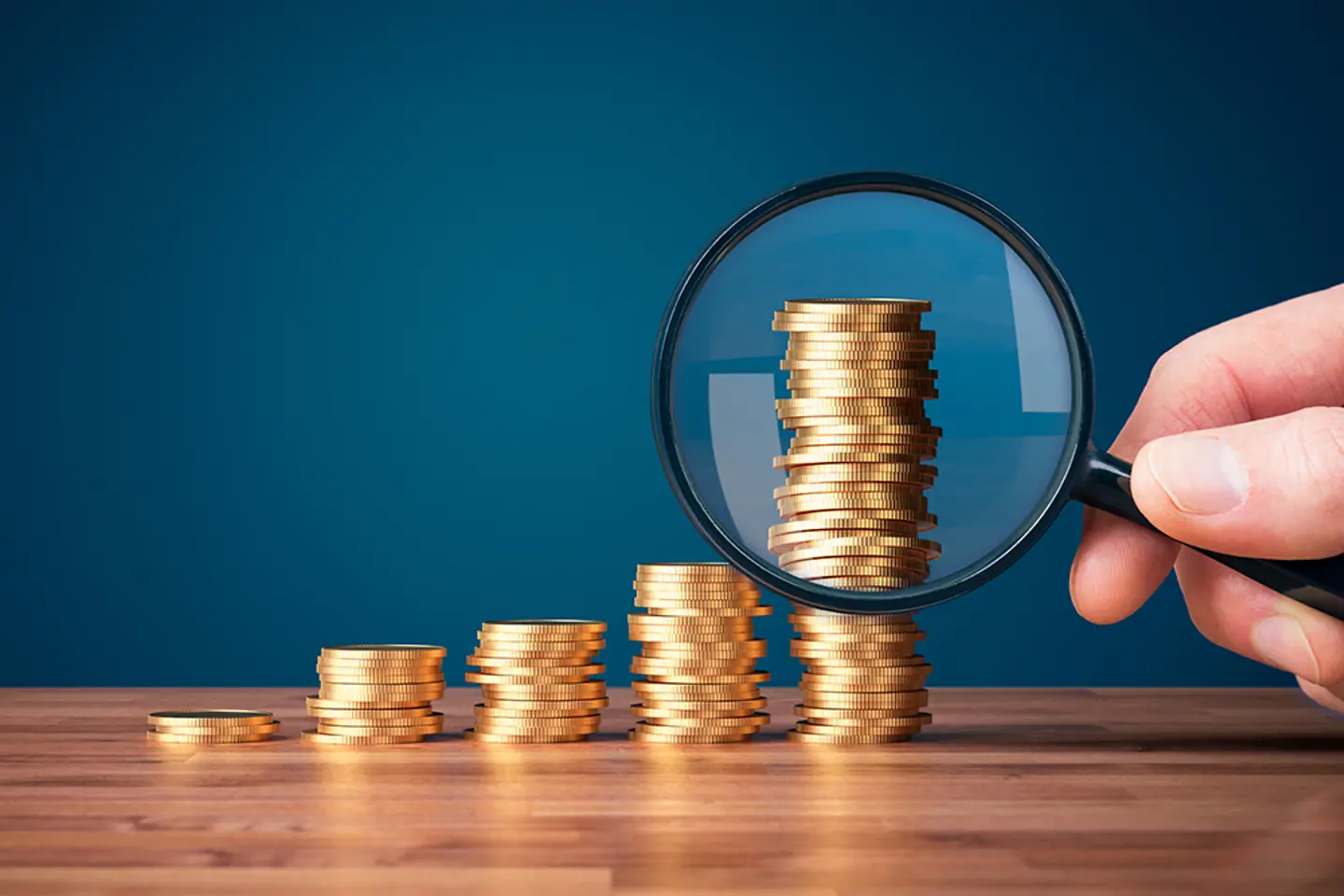 Monedas apiladas con una lupa en primer plano