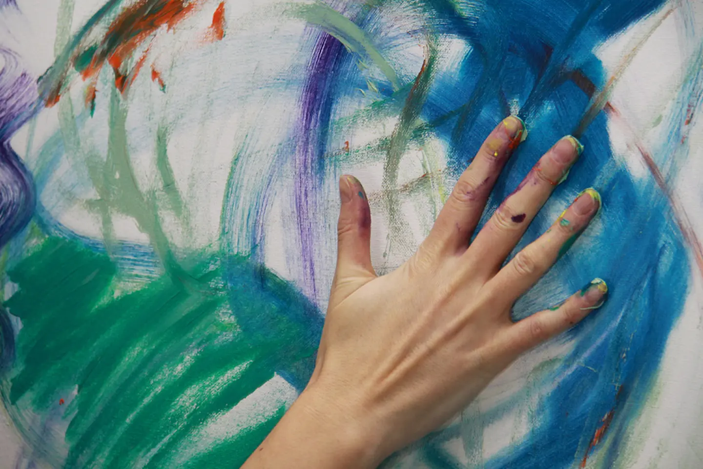 An artist paints with his hands on a canvas.