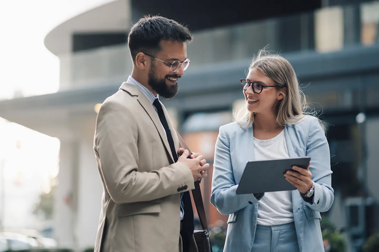Business people having conversation about work outdoors while using digital tablet