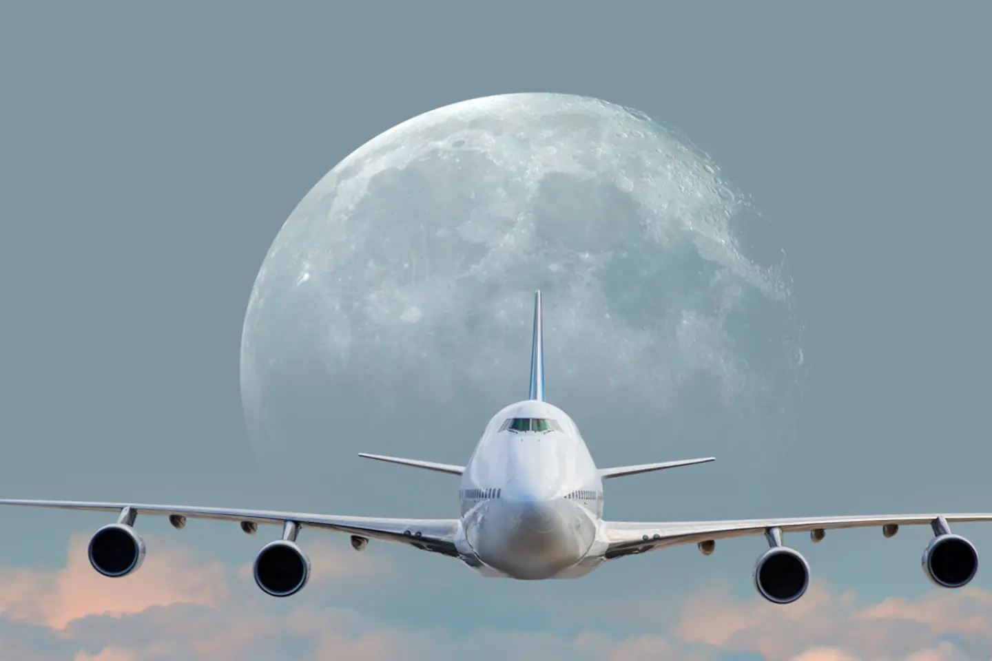 White passenger airplane in the clouds with full moon
