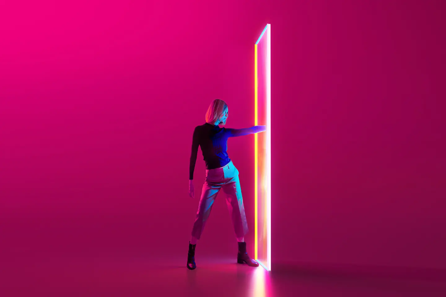 Digitaal gegenereerde foto van een jonge vrouw tegen een rode achtergrond, die een hand door een felgekleurd portaal steekt.