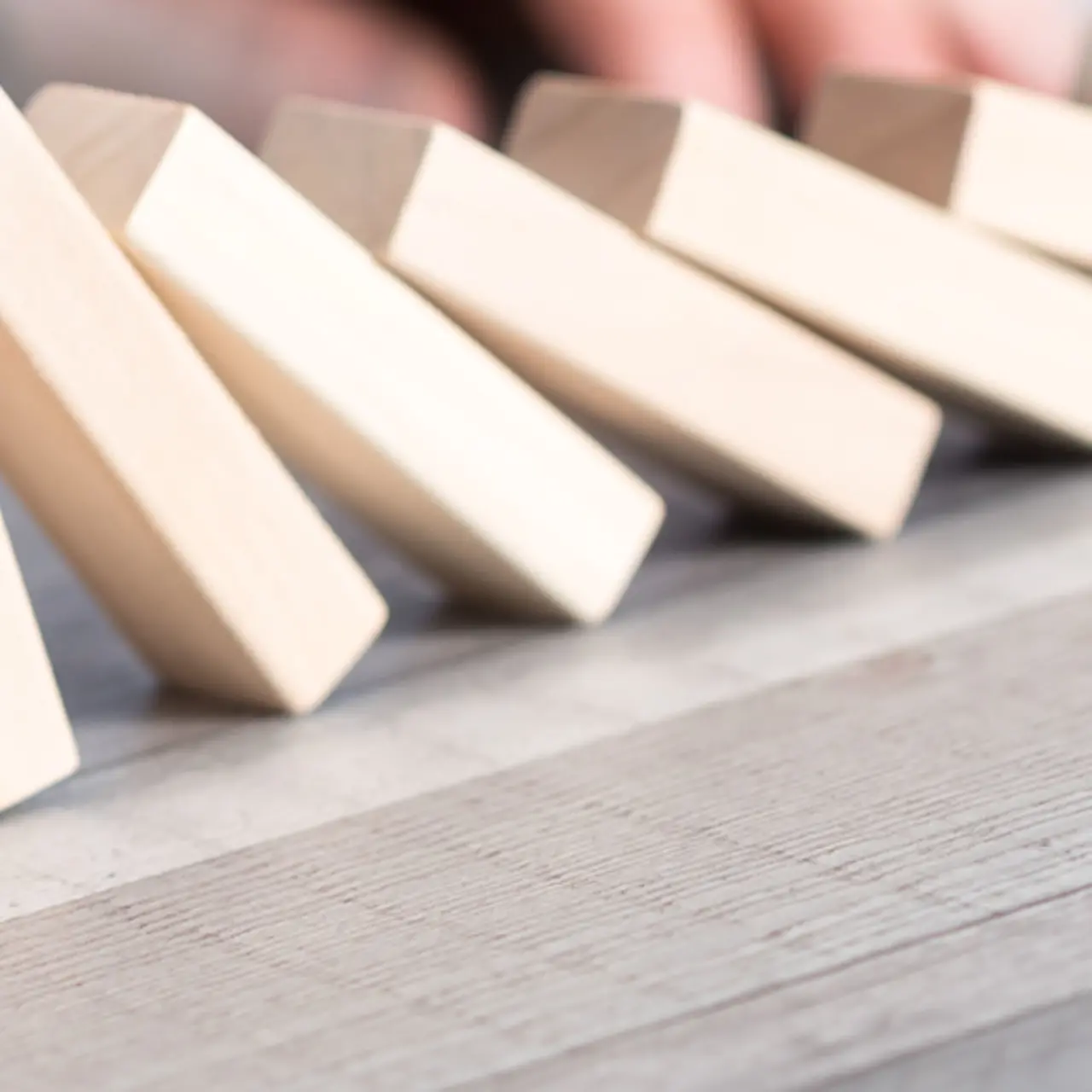 Hand stoppt Domino Steine vor dem Fallen