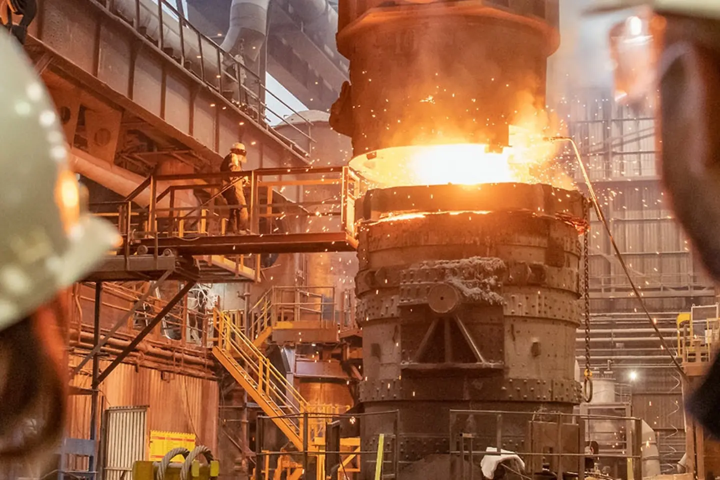 Twee staalarbeiders, een vrouw en een man, kijken naar een gieterij.