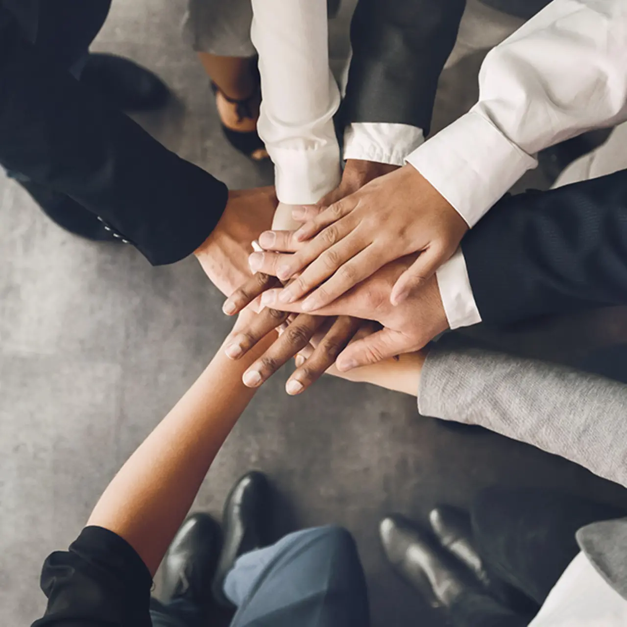 Team zeigt mit Hände verbinden Zusammenhalt