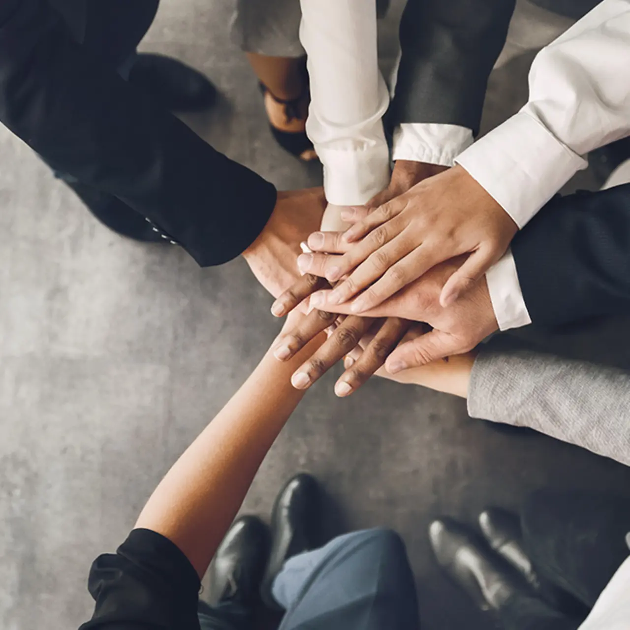 Team zeigt mit Hände verbinden Zusammenhalt