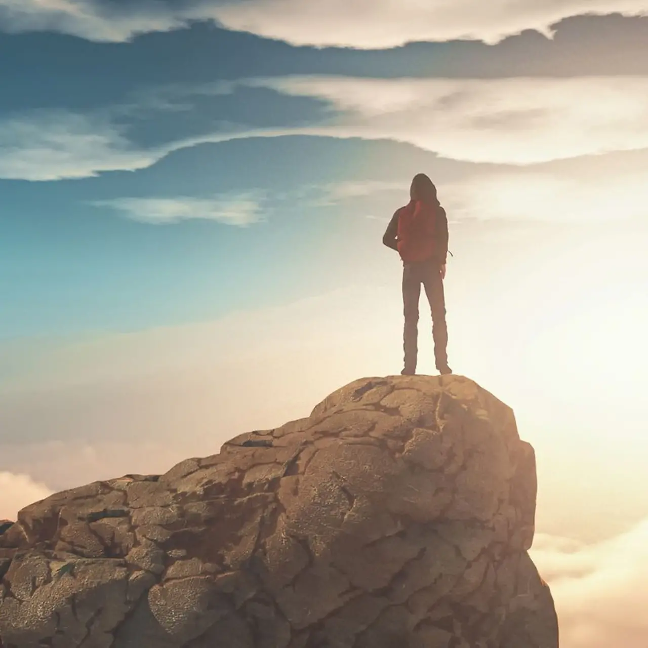 A man standing on a mountain top surrounded by clouds