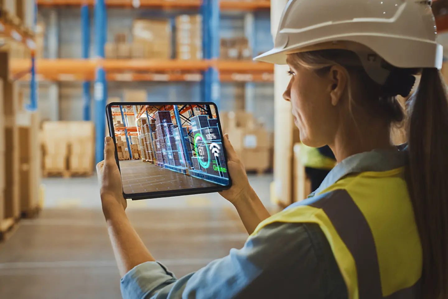 Empleada joven haciendo inventario en el almacén mediante realidad aumentada con una tableta digital.