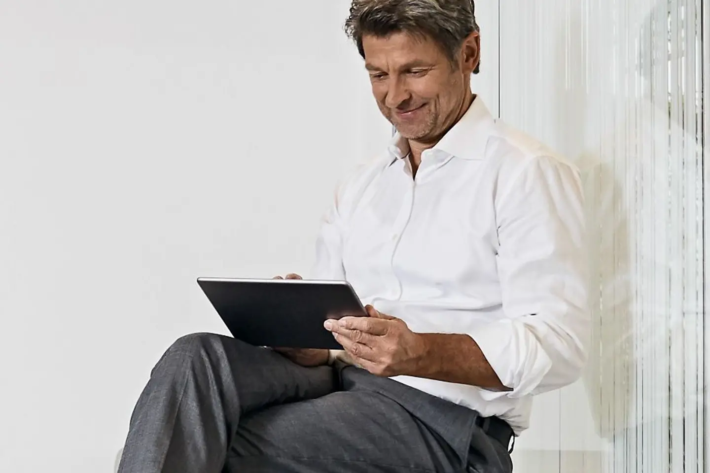 Mann sitzt mit einem Tablet in der Wohnung