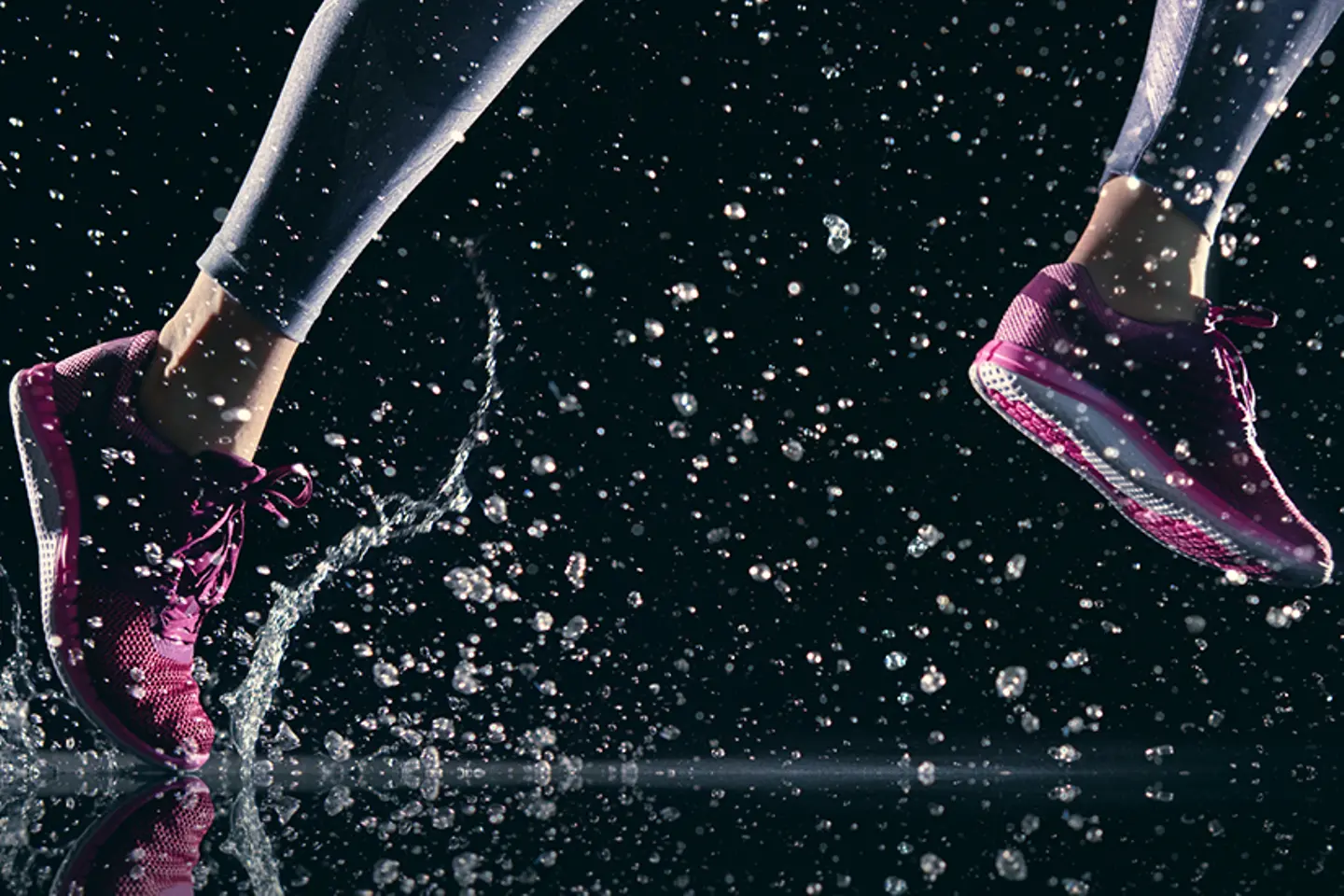 Läuferin tritt vor dunklem Hintergrund in Pfütze